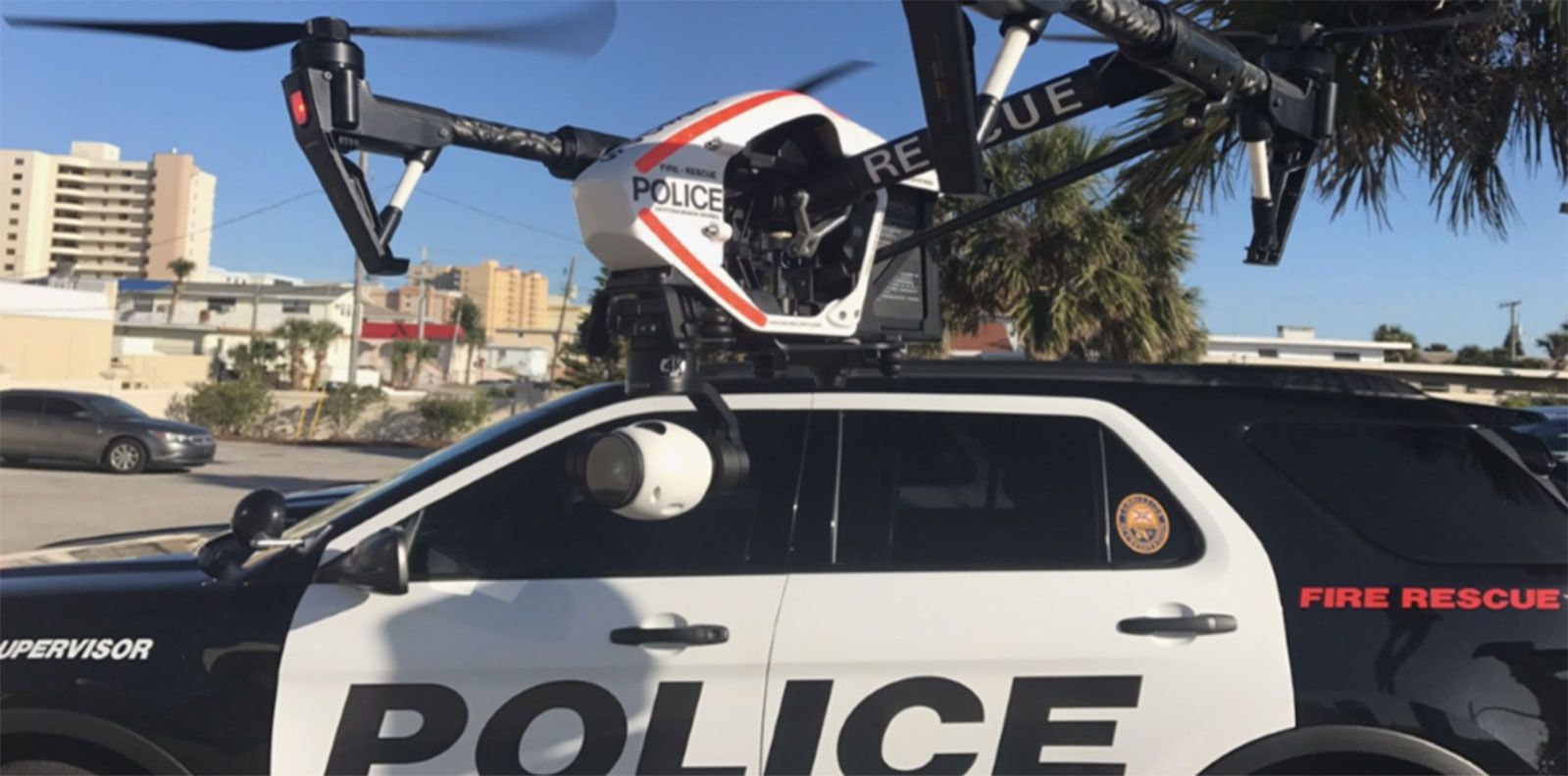 Image of drone flying next to police car